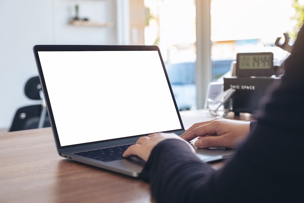 Mockup image of a woman using and typing on laptop with blank white desktop screen