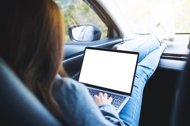 車の中で空白のデスクトップ画面でラップトップコンピューターを使用して作業している女性のモックアップ画像