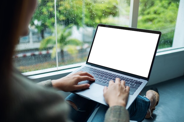 Immagine mockup di una donna che lavora e digita su un computer portatile con schermo vuoto mentre è seduta sul pavimento