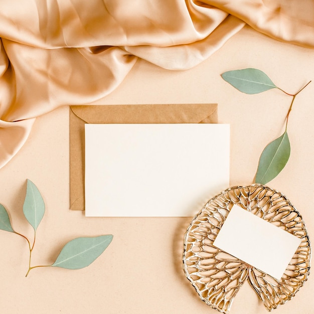 Mockup invitation blank greeting card and craft envelope green leaves eucalyptus flat lay top view