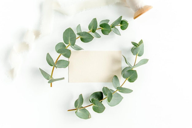 Mockup invitation blank greeting card and green leaves eucalyptus flat lay top view