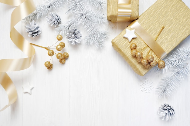 Mockup kerst cadeau gouden boog lint en boom kegel, flatlay op een witte houten achtergrond.