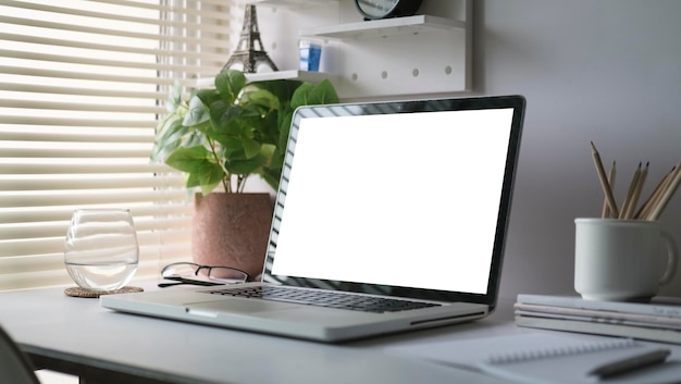モックアップ ラップトップ コンピューター コーヒー カップ ノートとホーム オフィスの白いテーブルの上の鉢植えの植物