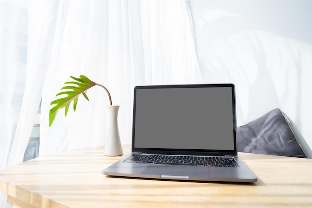 Mockup of laptop computer with empty screen on table of the coffee shop outdoor backgroundgray screen