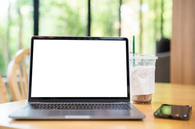 Photo mockup of laptop computer with empty screen with coffee cup and smartphone on table of the coffee shop backgroundwhite screen