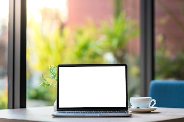 Mockup of laptop computer with empty screen with coffee cup on table of the coffee shop backgroundWhite screen