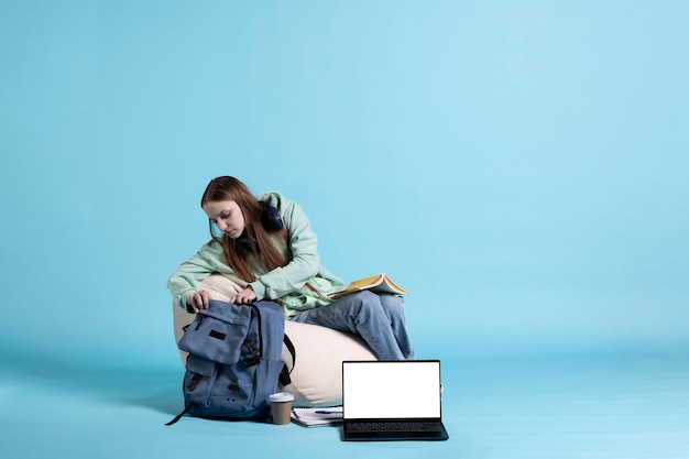 バックパックをブラウジングしている学生の隣にあるモックアップのラップトップ