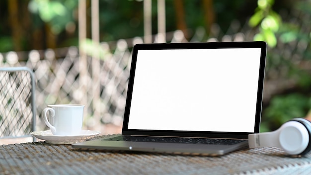 Mockup Laptop white screen and coffee mug on table with nature background.