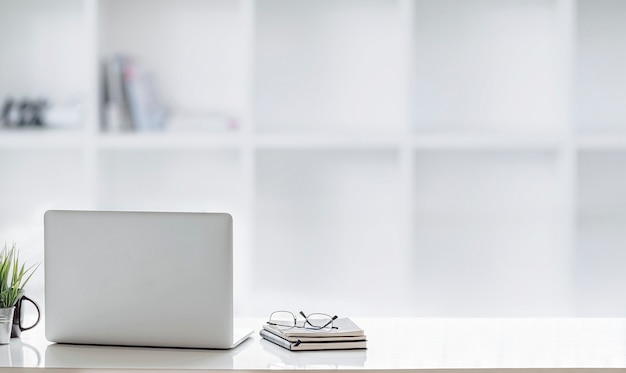 Photo mockup laptop on white top table in white office room.