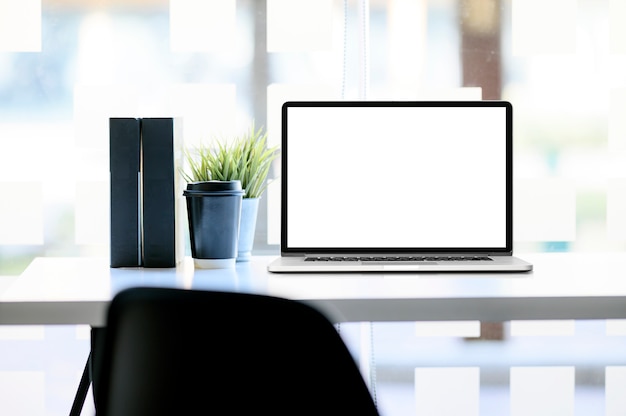 Photo mockup laptop with blank screen and supplies on wooden table.