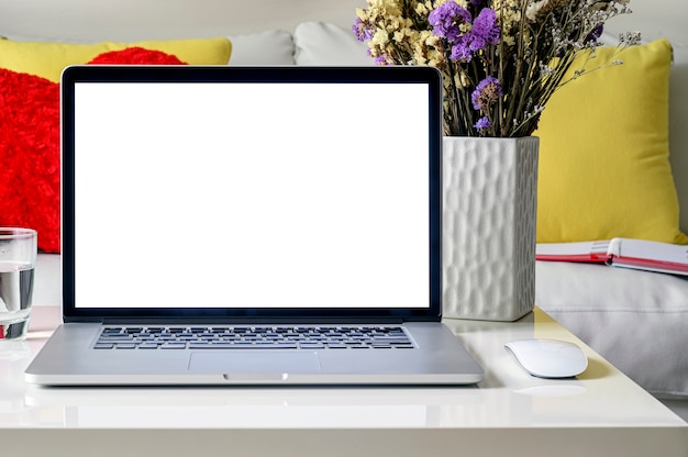 Mockup laptop with blank screen on white table in living room.