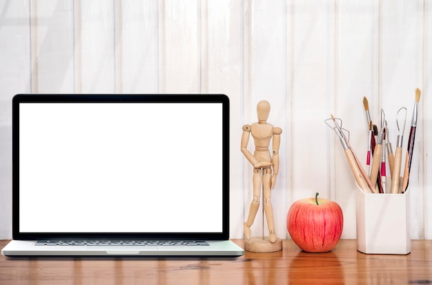 Mockup laptop with blank screen on wooden table and white wooden wall.