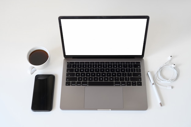 Computer portatile del modello con la tazza da caffè sullo scrittorio bianco.