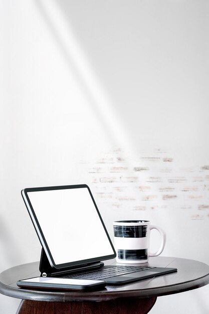 Mockup leeg scherm tablet met toetsenbord en smartphone op houten salontafel in witte kamer