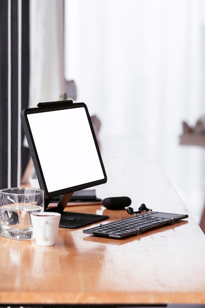 Mockup leeg scherm tablet met toetsenbord op houten aanrechttafel in café, verticale weergave.