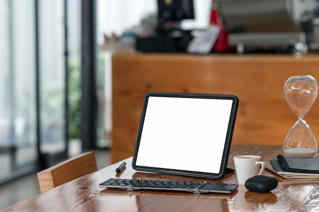 Mockup leeg scherm tablet met toetsenbord op houten tafel in café kamer.