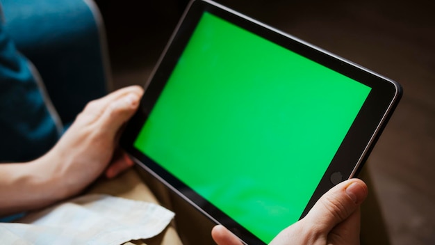 A mockup of a man holds a tablet computer with chroma key screen in his hands Top view