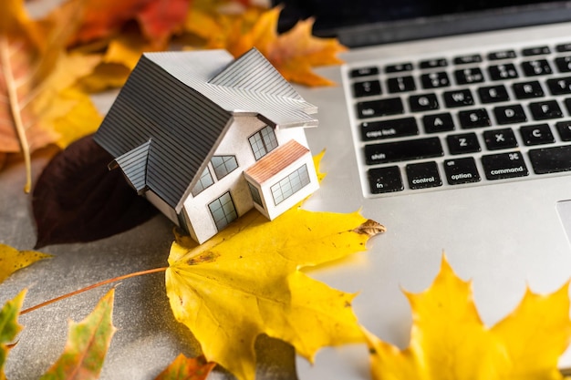 mockup model huis en bladeren in de buurt van laptopcomputer op een tafel. Herfst seizoen tijd