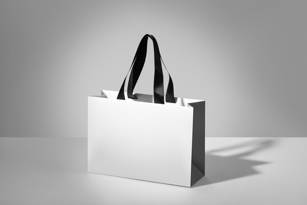 写真 黒いハンドルを持つロゴのない白い紙袋のモックアップ 灰色の背景の白いパッケージ