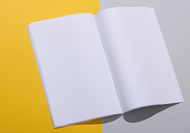 灰色の黄色い背景の白い開いたページのオープン雑誌のモックアップ デザインのテンプレート