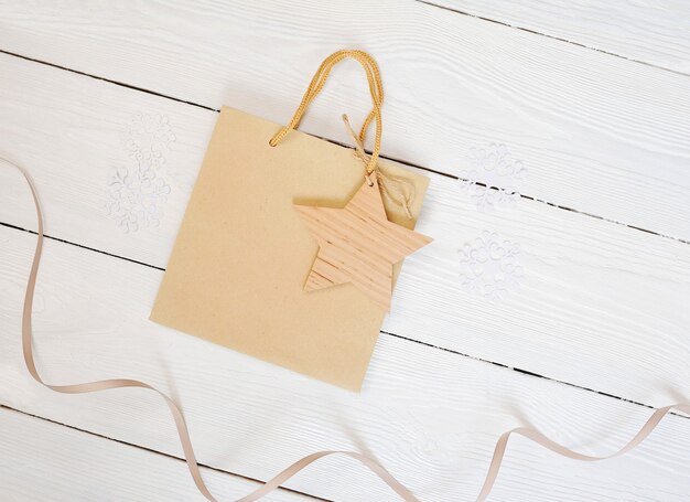 Mockup Paper bag from kraft paper with gift tag star and on a wooden background. Flat lay, top view photo mock up.