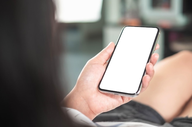 Mockup phone in woman hand showing white screen at home taken from the rear viewminimal concept