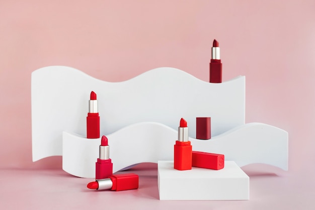 Mockup of red lipsticks on a white staircase with geometric shapes and a podium