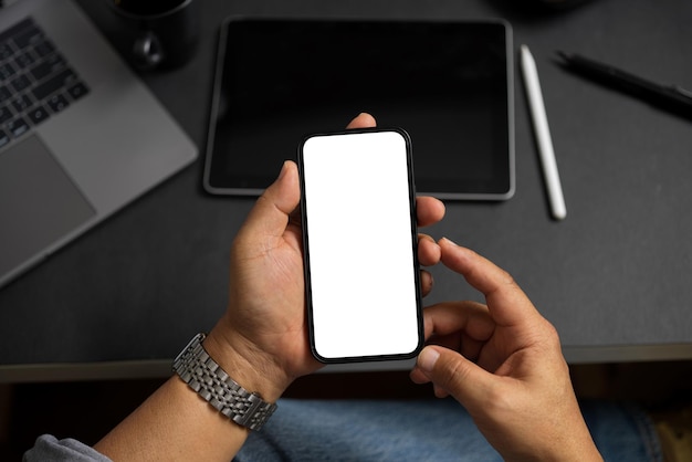 Mockup-scherm van een moderne smartphone in de handen van een mannelijke of volwassen man over een kantoortafel. Detailopname