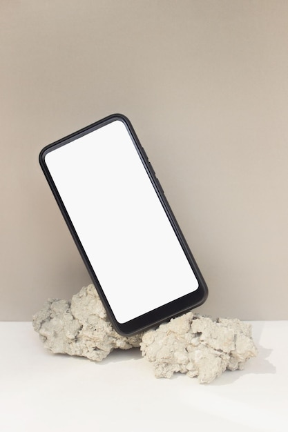 Mockup sjabloon smartphone balanceren op natuursteen op beige achtergrond. Telefoon met leeg scherm