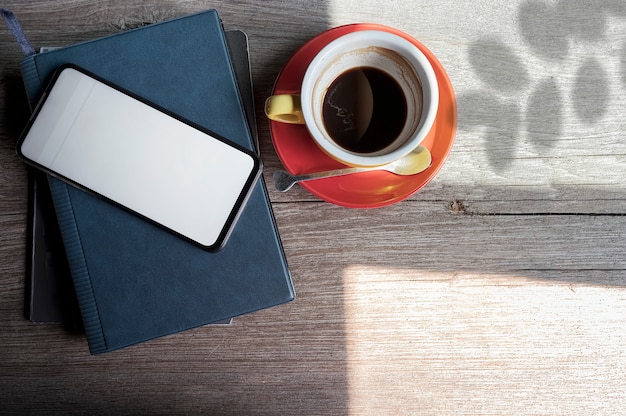 Mockup smartphone wit leeg scherm en kopje koffie op houten bovenste tafel.