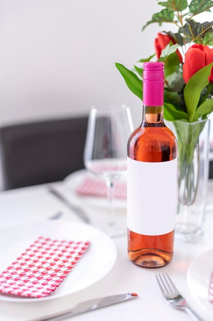 Foto mockup di una bottiglia di vino a rose in piedi su un tavolo da pranzo alla luce naturale.