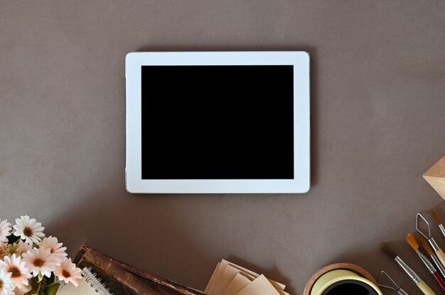 Mockup tablet on creative workplace with top view on brown table background.