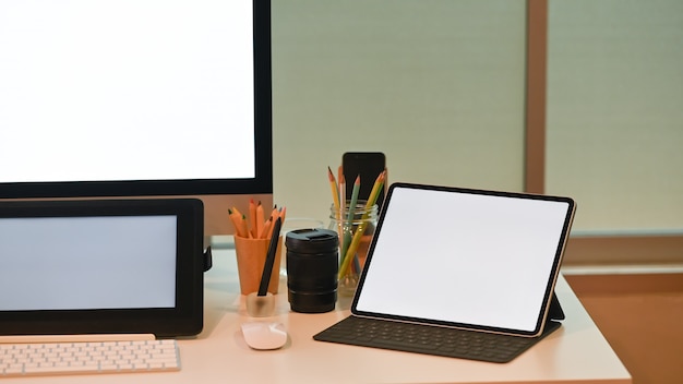 Mockup tablet pc op creatieve werkruimte met lege scherm computerapparatuur.