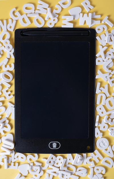 Макет планшета среди трехмерных букв из гипса на желтом фоне Концепция учебных презентаций