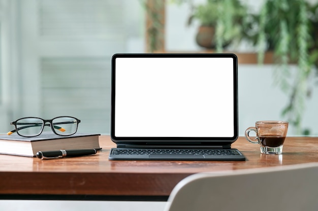 Mockup tablet with magic keyboard on wooden table in cafe with blank screen.