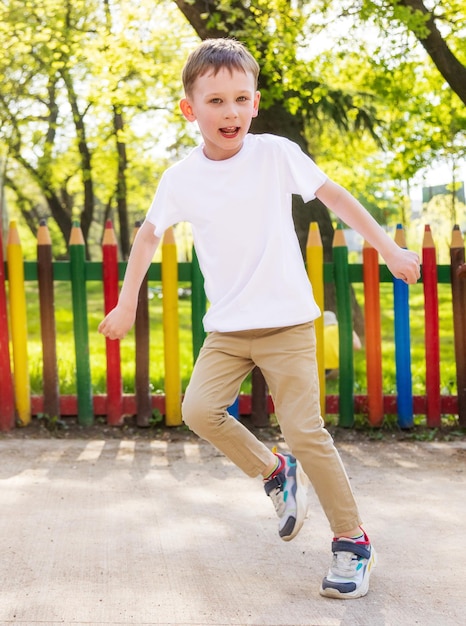 Mockup template A cheerful boy in a white Tshirt is dancing in the park