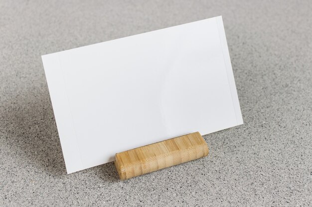 Modello di mockup con carta fotografica in bianco su supporto in legno su superficie punteggiata grigia.