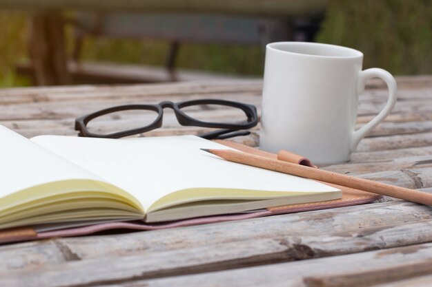 Photo mockup top view of notebook with pencil glass coffee cup on bamboo wood table