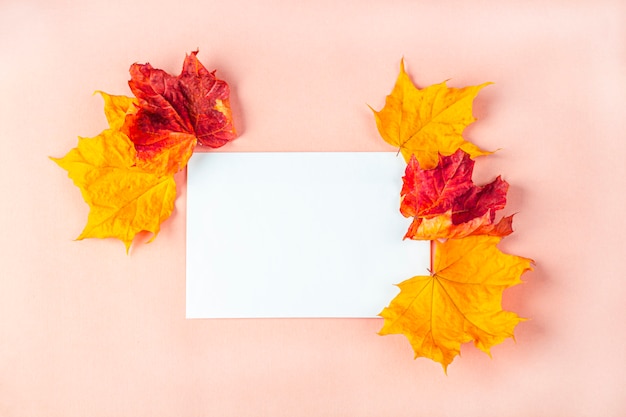 Mockup uitnodigingskaart. Sjabloon leeg wenskaart voor de bruiloft, verjaardag en andere evenementen. Papier op perzik kleur achtergrond met droge herfstbladeren.