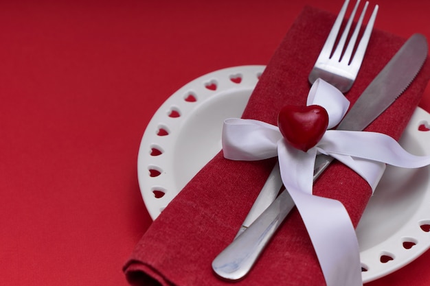 Mockup Valentines day. White plate in the shape of a heart and silver cutlery