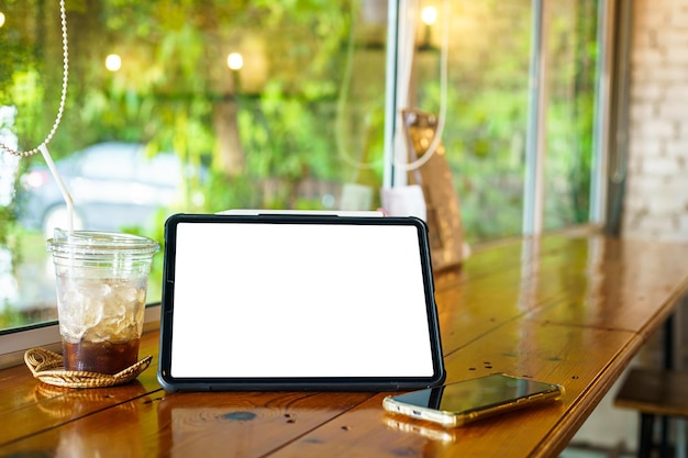 Mockup van digitale tablet met leeg scherm met koffie en smartphone isoleren op houten bureau in coffeeshop zoals de achtergrond Wit scherm