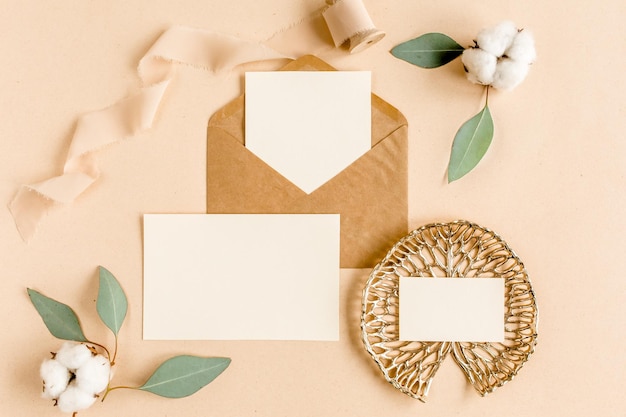 Макет свадебного приглашения, пустая открытка и конверт с зелеными листьями эвкалипта, плоская планировка