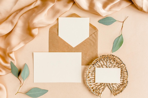 Photo mockup wedding invitation blank greeting card and craft envelope green leaves eucalyptus flat lay