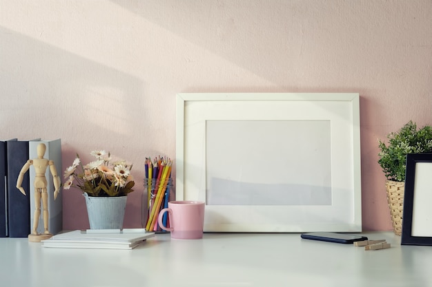 Mockup-werkruimtetafel met wit posterkader, koffiemok, notitieboekje en levering.