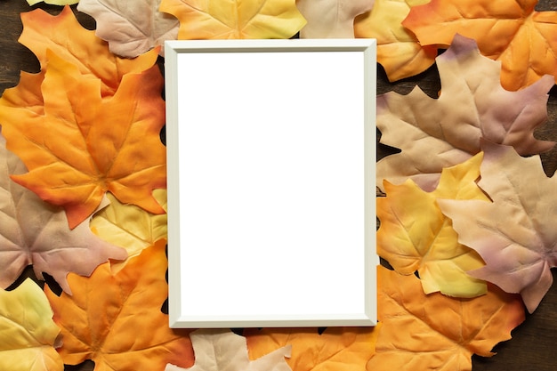 mockup white blank paper frame with group of dried orange color maple leaves background