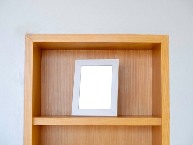白い四角い額縁のモックアップ縦型木製食器棚の一番上の棚にある空白の白い額縁ミニマルスタイル
