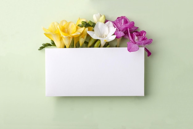 Photo mockup with blank rectangular sheet of paper and colorful freesia flowers with copy space