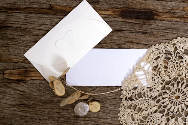 Макет с чистым прямоугольным листом бумаги и конвертом на деревянном столе