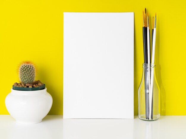 Mockup with clean white canvas, cactus, brushes on bright yellow background. Concept for c