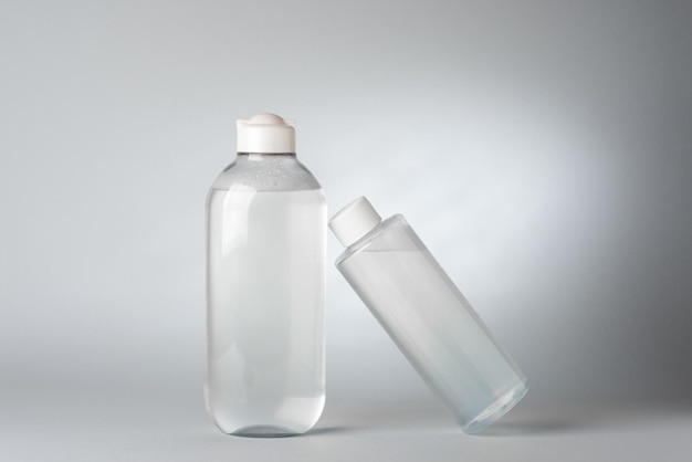 Mockup with two clean bottles of micellar water on gray background